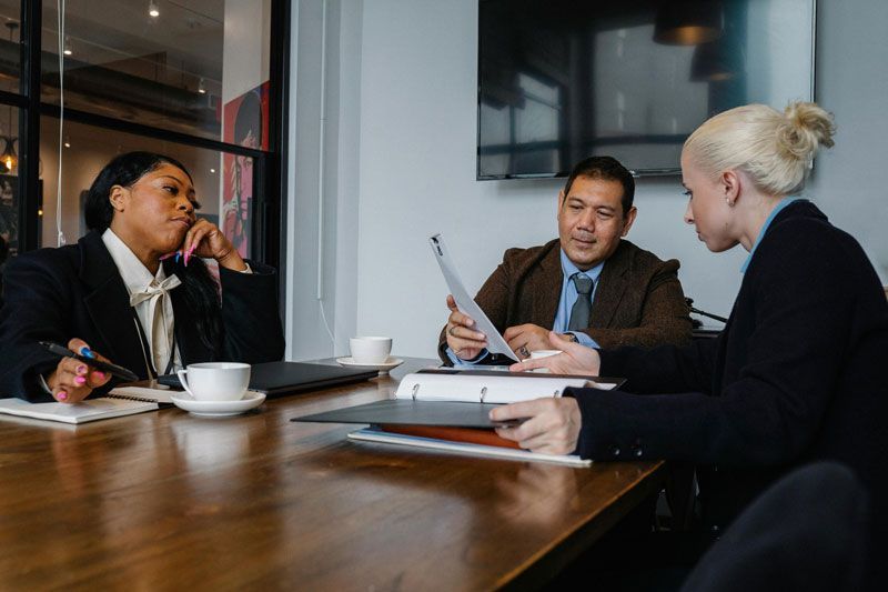 Job seeker meeting with recruiters at conference table in an office.