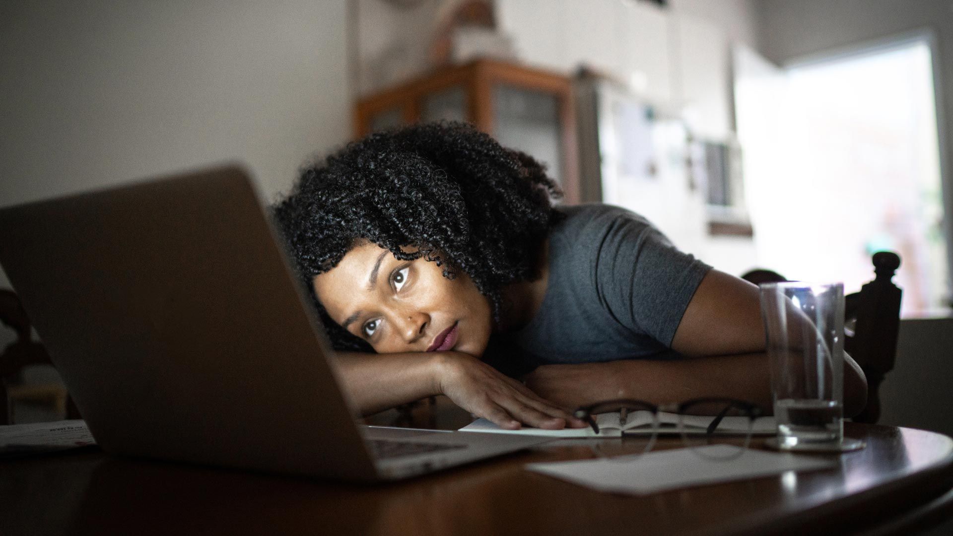 executive job seeker at home exhausted sitting at computer contemplating next steps in job search