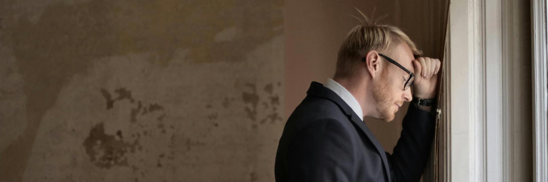 downtrodden executive leaning against wall after not landing the job offer yet again