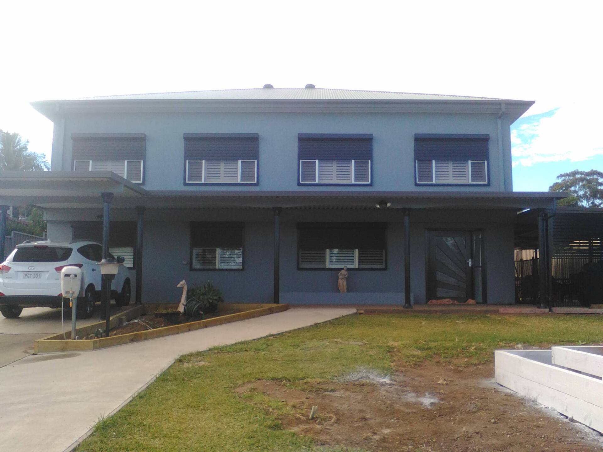 A large blue house with a white car parked in front of it.