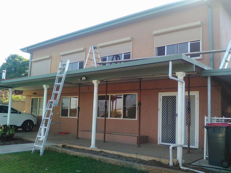 A house with a ladder on the side of it and a car parked in front of it.