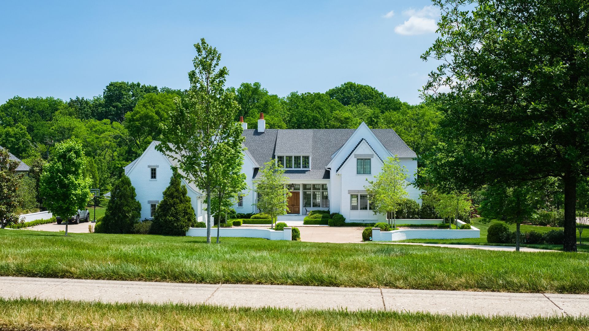 Modern white living room with a beige sectional sofa, arched windows, and a geometric patterned armchair.