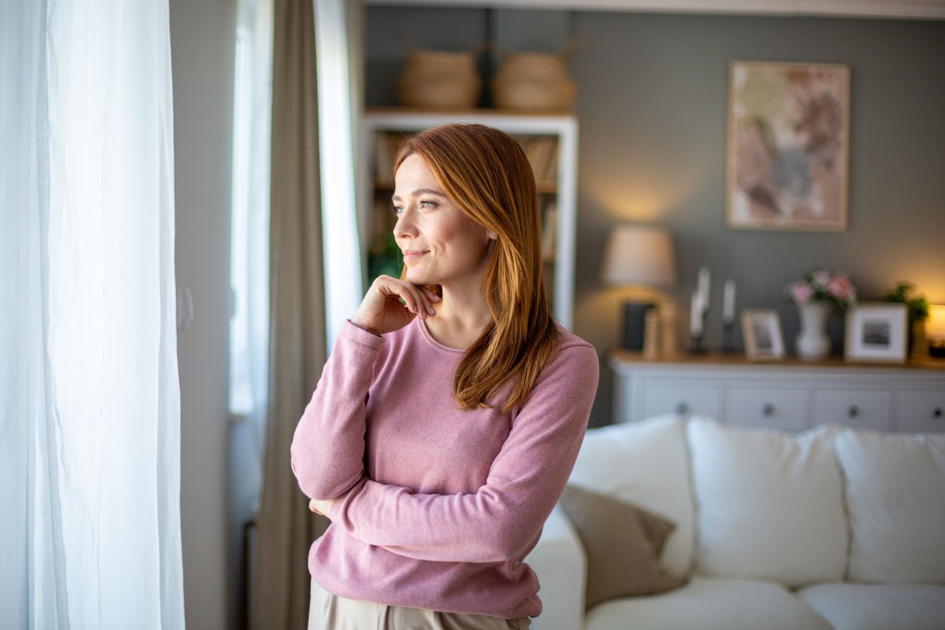 Modern white living room with a beige sectional sofa, arched windows, and a geometric patterned armchair.