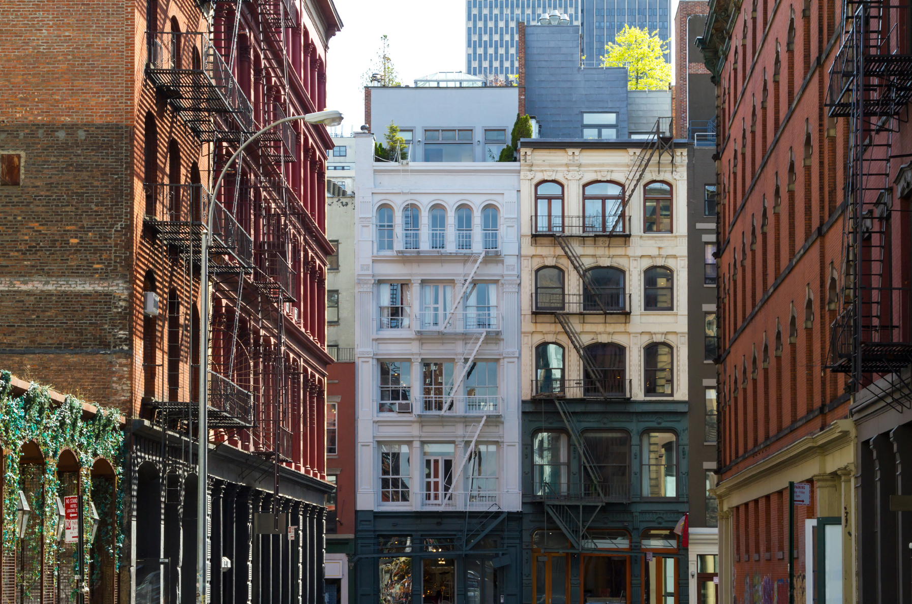 Modern white living room with a beige sectional sofa, arched windows, and a geometric patterned armchair.
