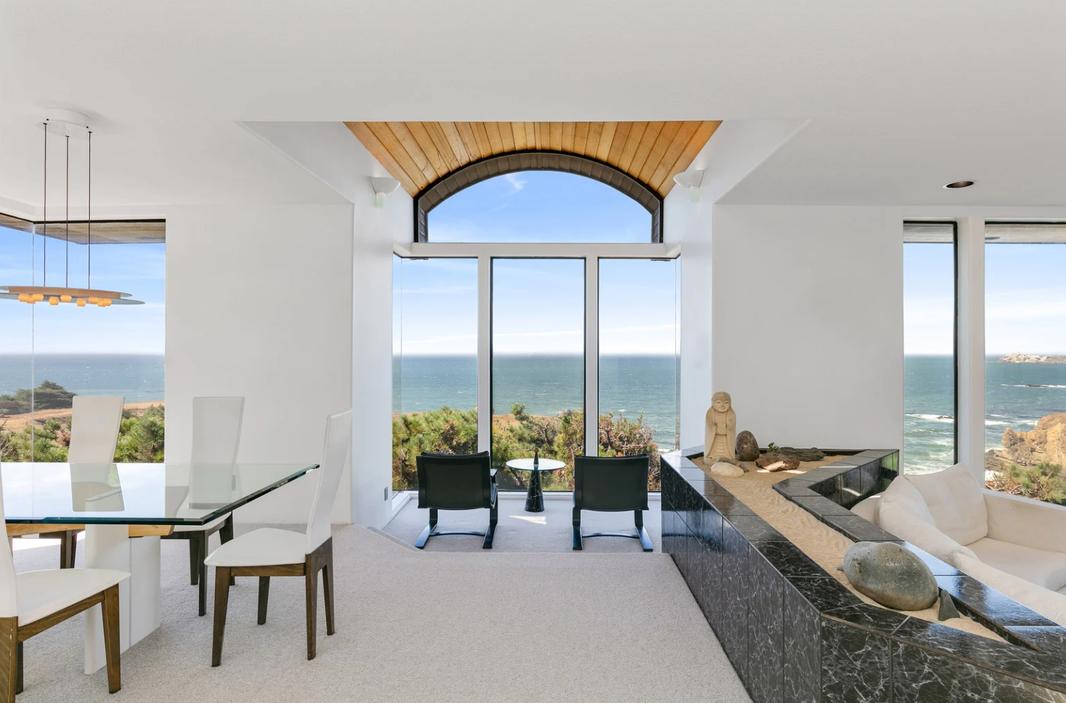 Modern white living room with a beige sectional sofa, arched windows, and a geometric patterned armchair.