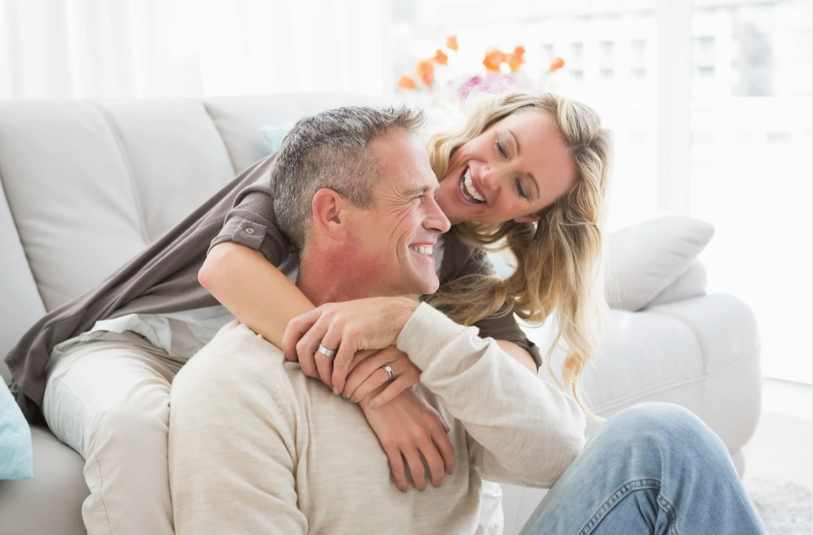 Modern white living room with a beige sectional sofa, arched windows, and a geometric patterned armchair.