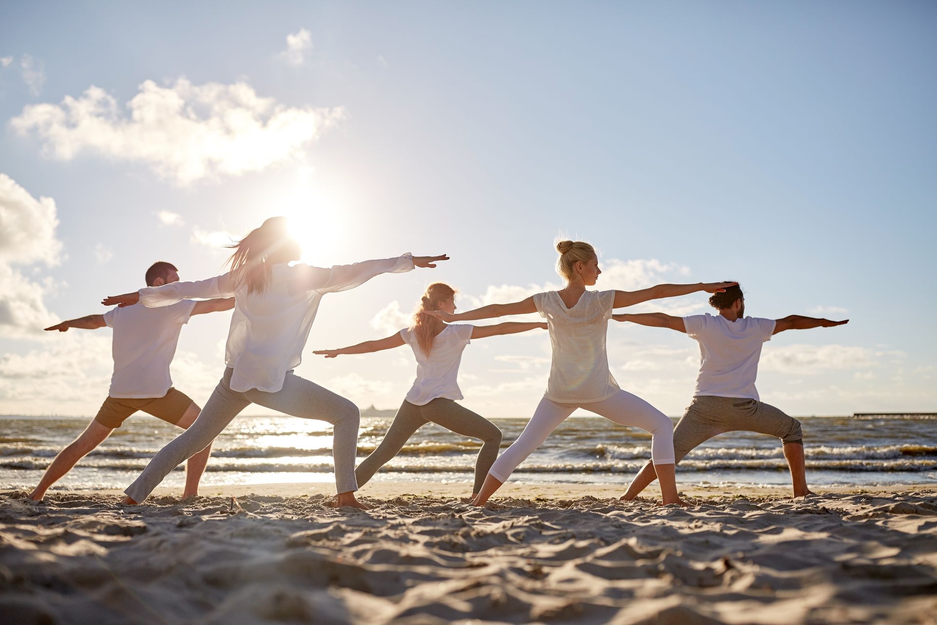 A group of people are practicing yoga on the beach.