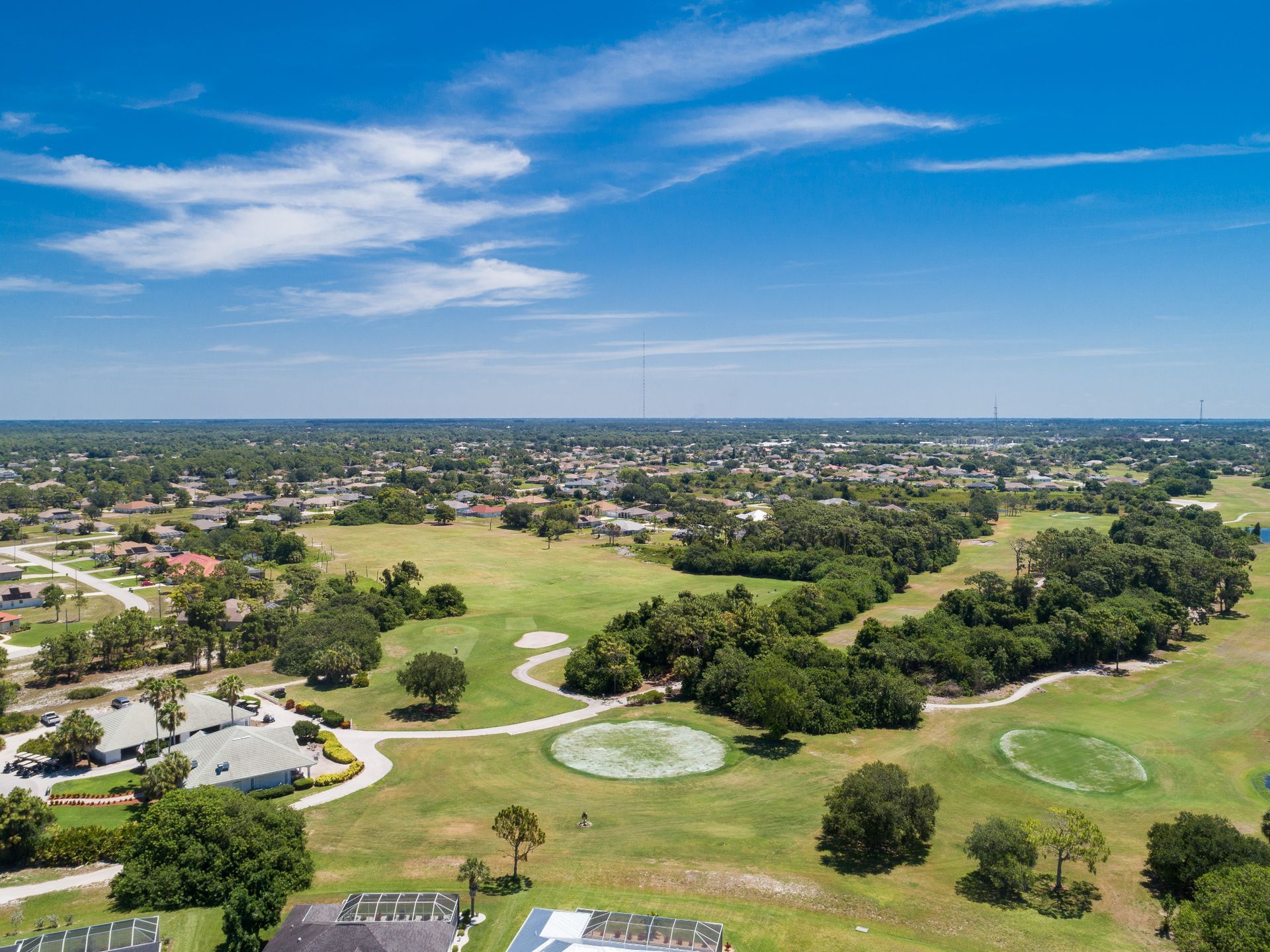 An aerial view of a golf course surrounded by trees and houses.