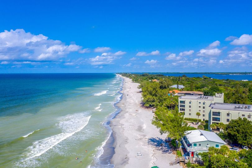 An aerial view of a beach with waves crashing on the shore.