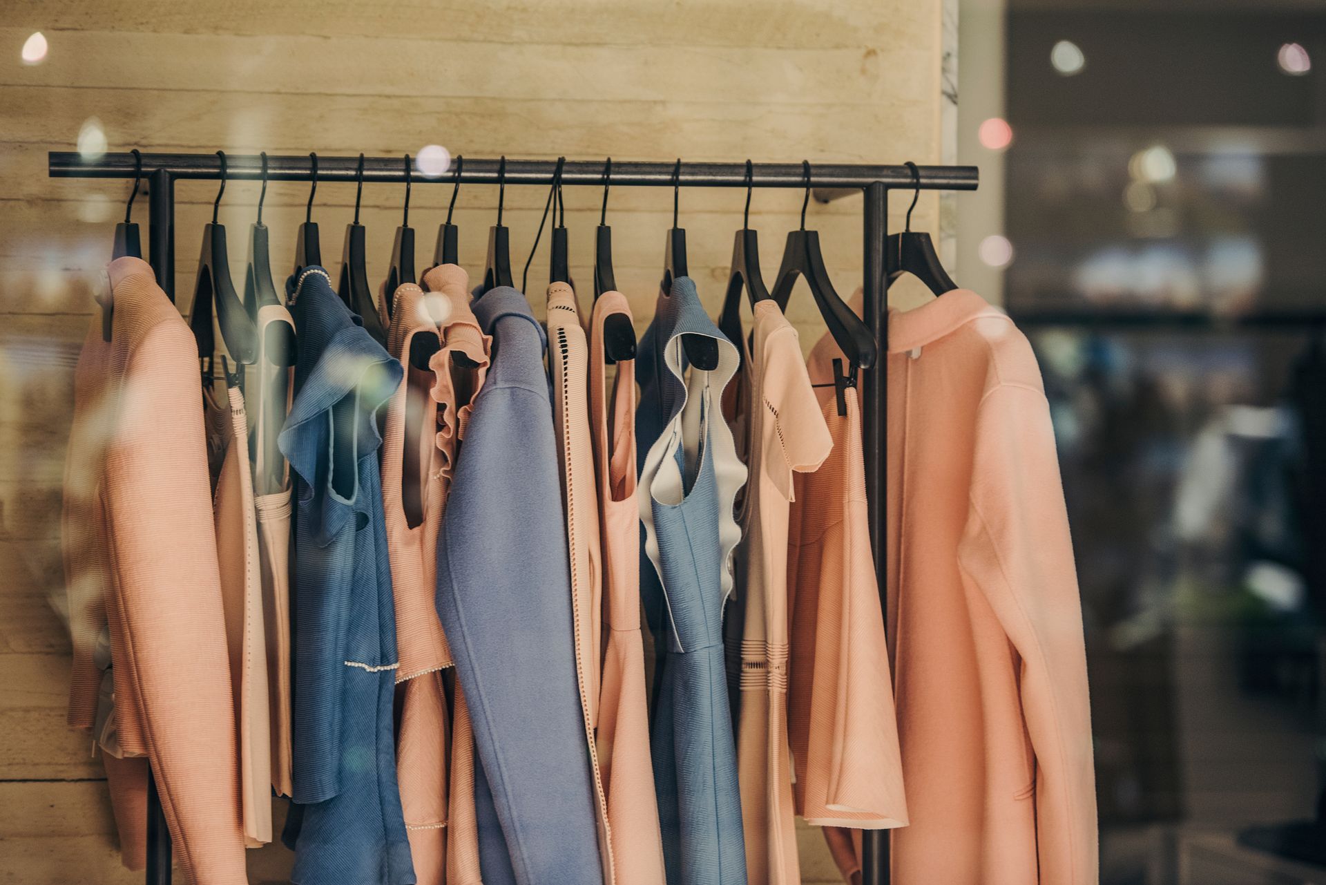 A row of clothes hanging on a rack in a store window.