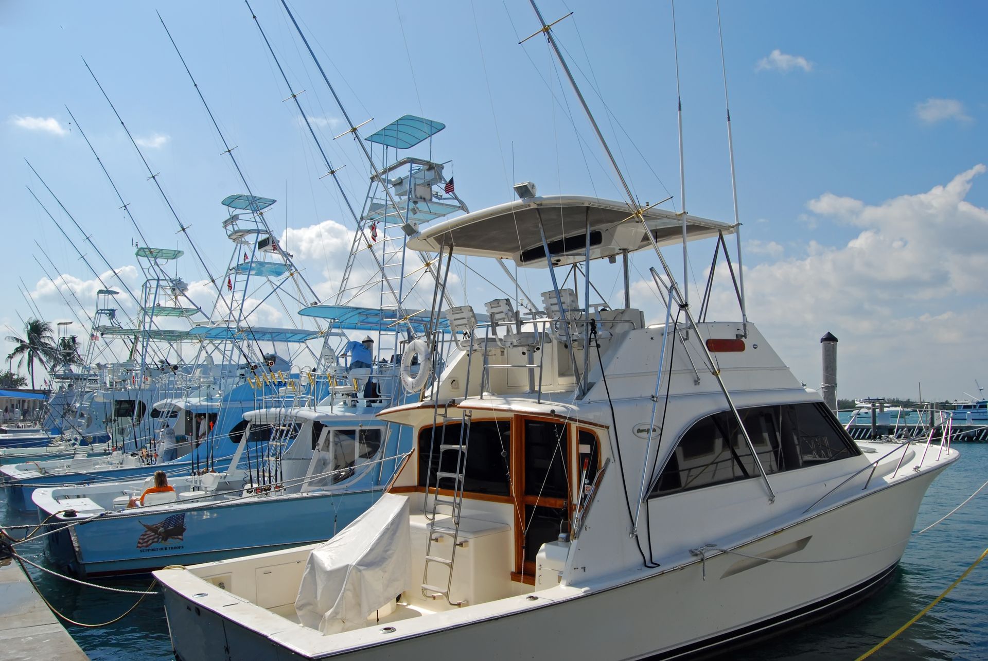 A row of fishing boats are docked at a marina