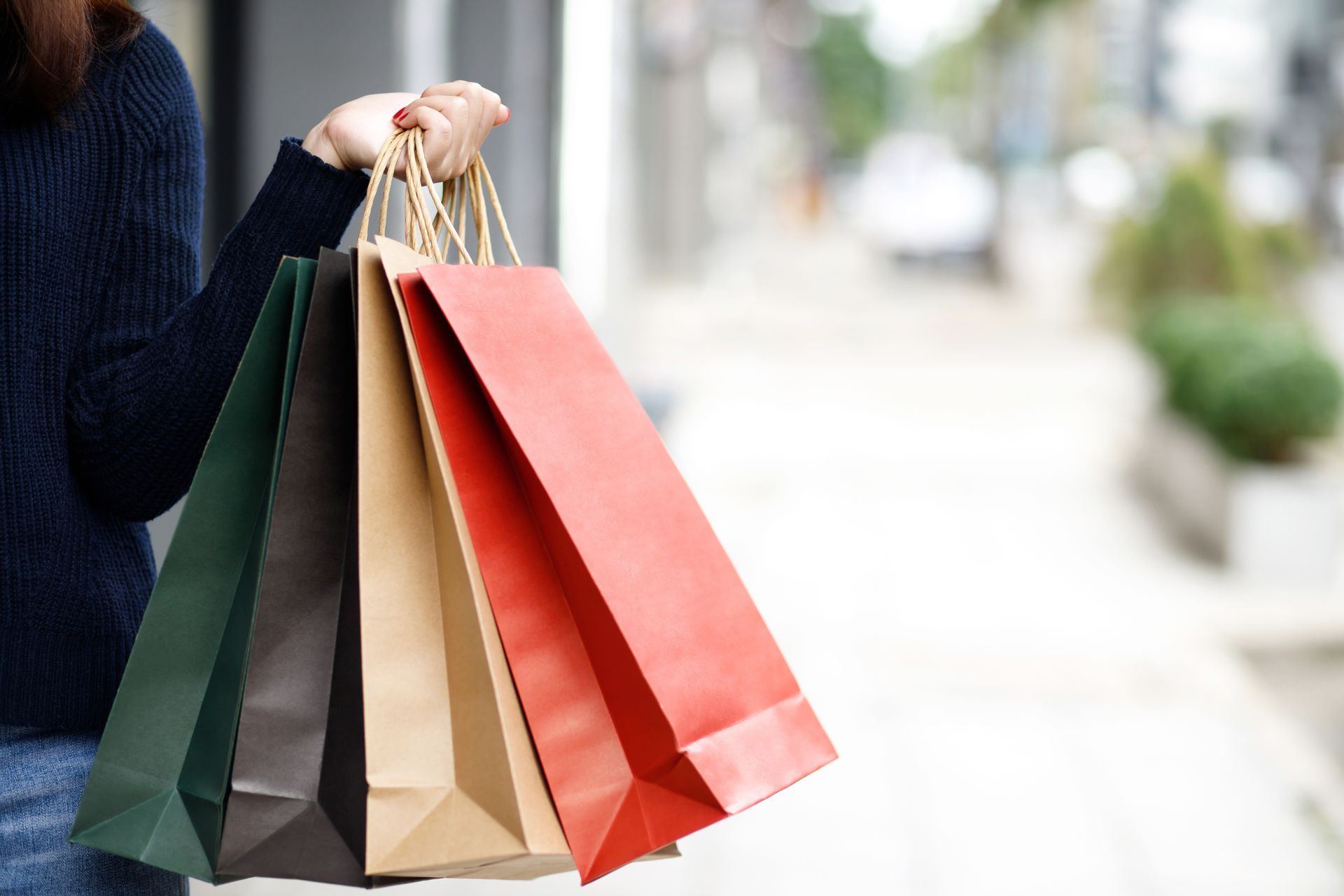 A woman is holding a bunch of shopping bags in her hands.