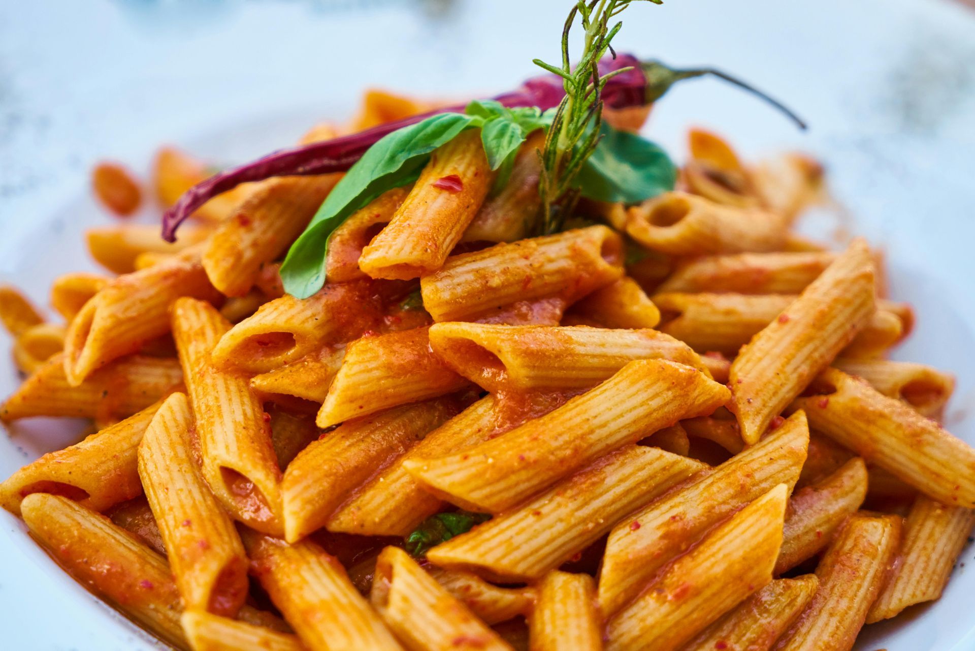 A plate of pasta with tomato sauce and basil on a table.