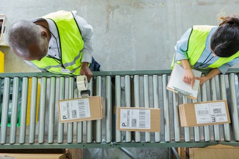 Male and female distribution warehouse employees process customers' orders.