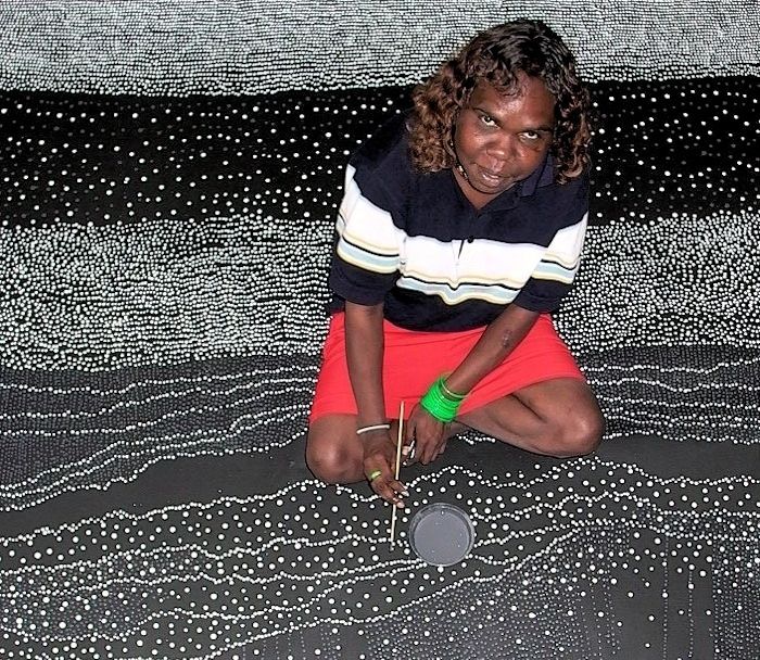 A woman in a black and white striped shirt and red skirt is kneeling down