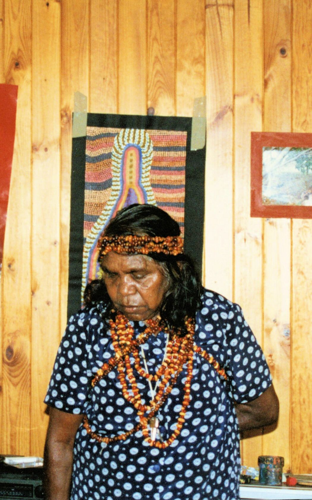A woman wearing a headband is standing in front of a wooden wall.