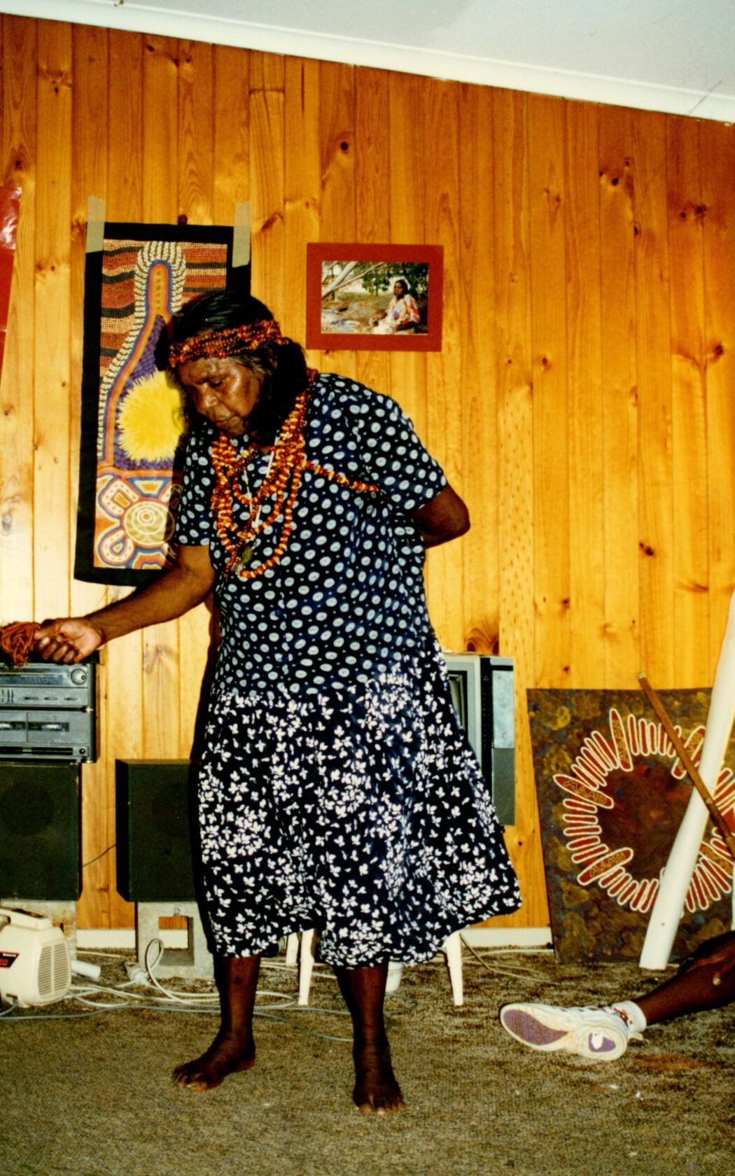 A woman in a polka dot dress is standing in front of a wooden wall
