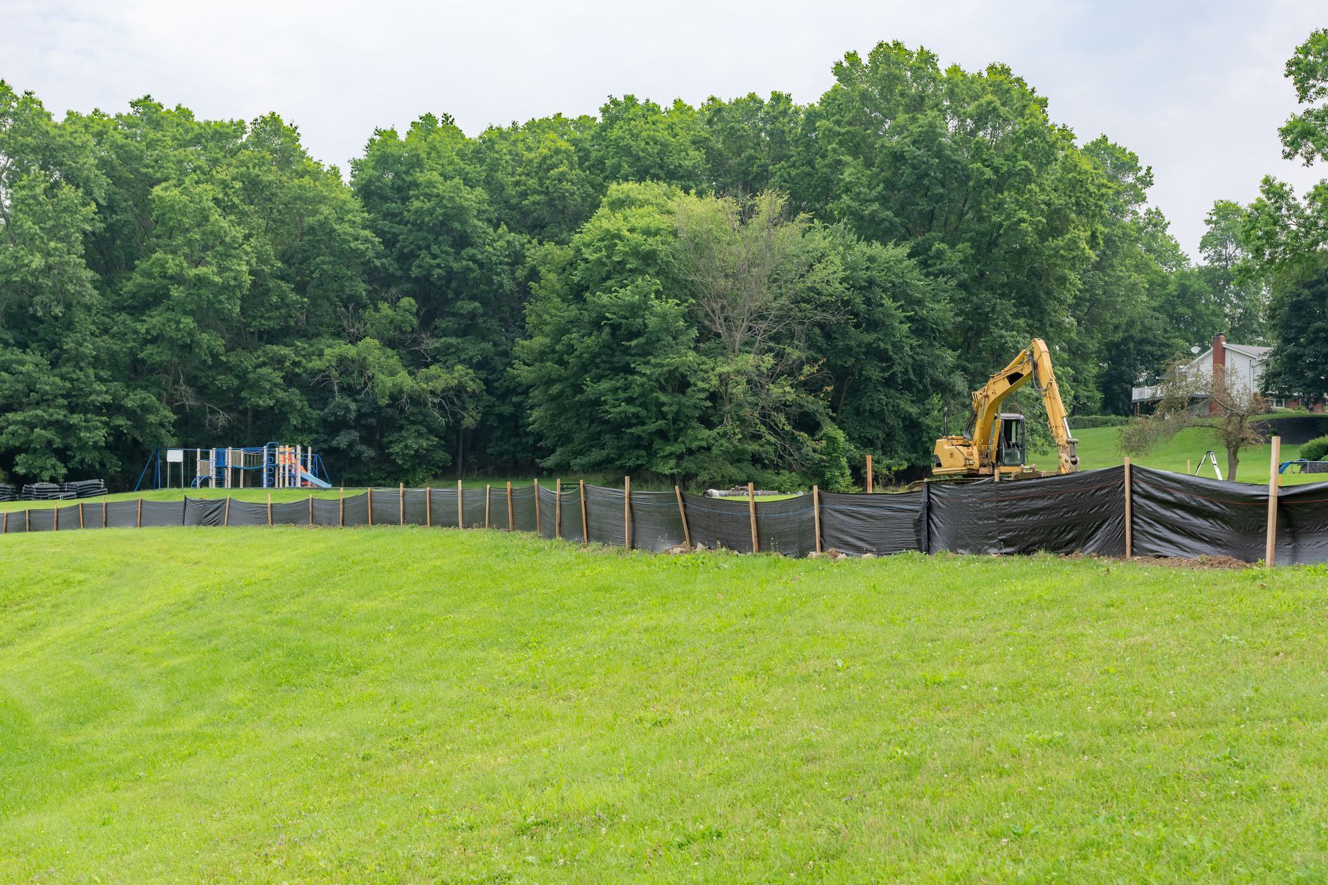 A large yellow excavator is sitting in the middle of a grassy field.