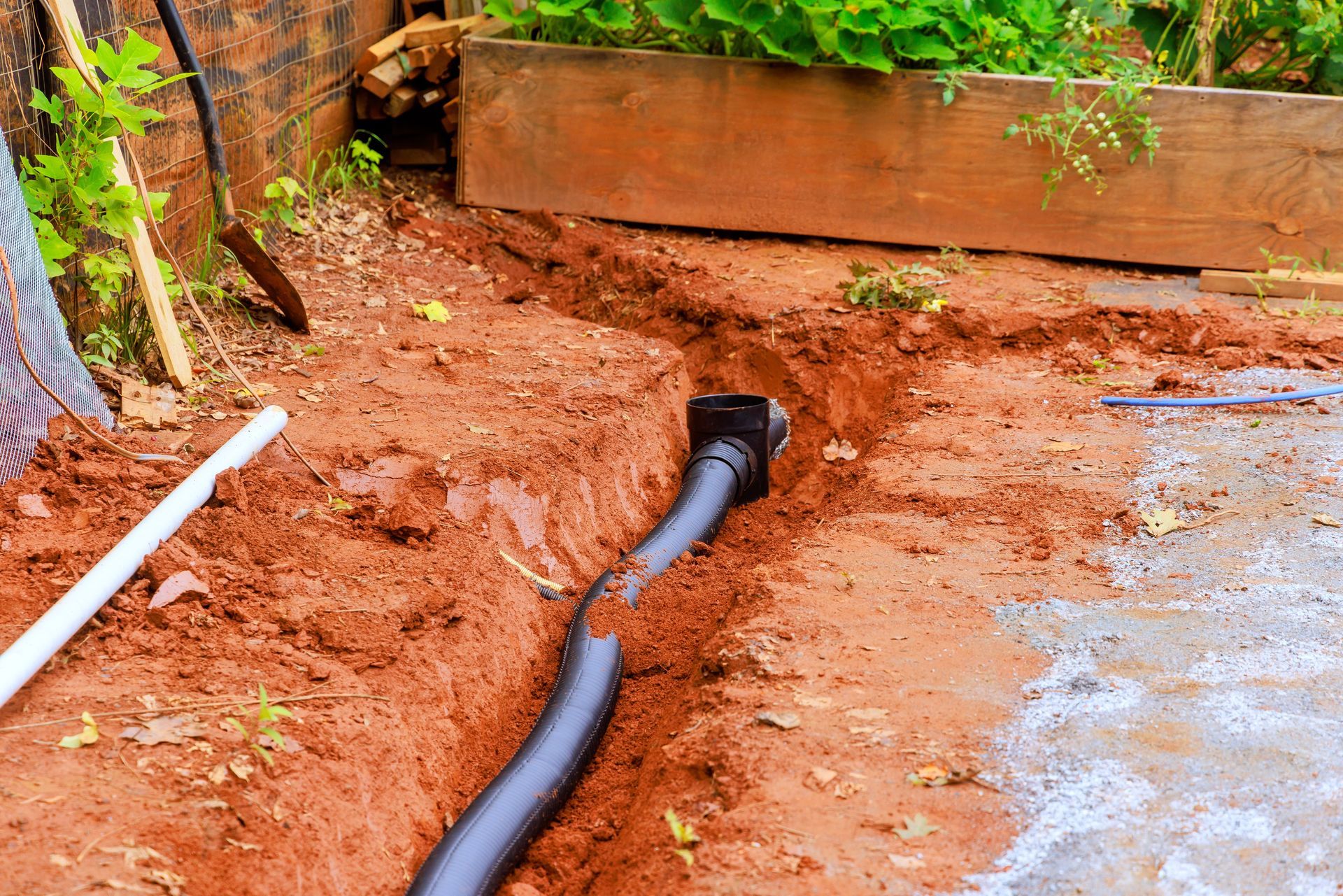 A black pipe is being installed in the dirt.