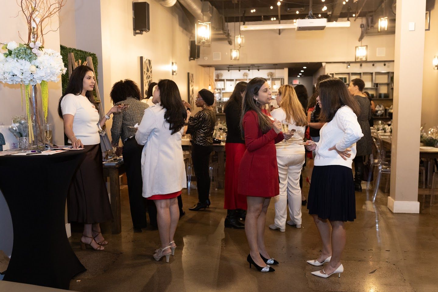 People mingling at an indoor networking event in a bright venue, with drinks and conversation.