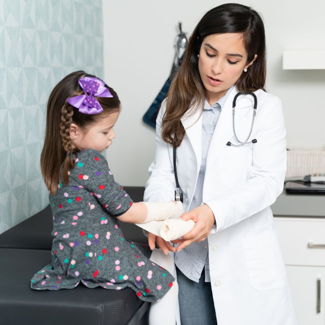 Doctor tending to a young child’s bandaged hand in a clinic