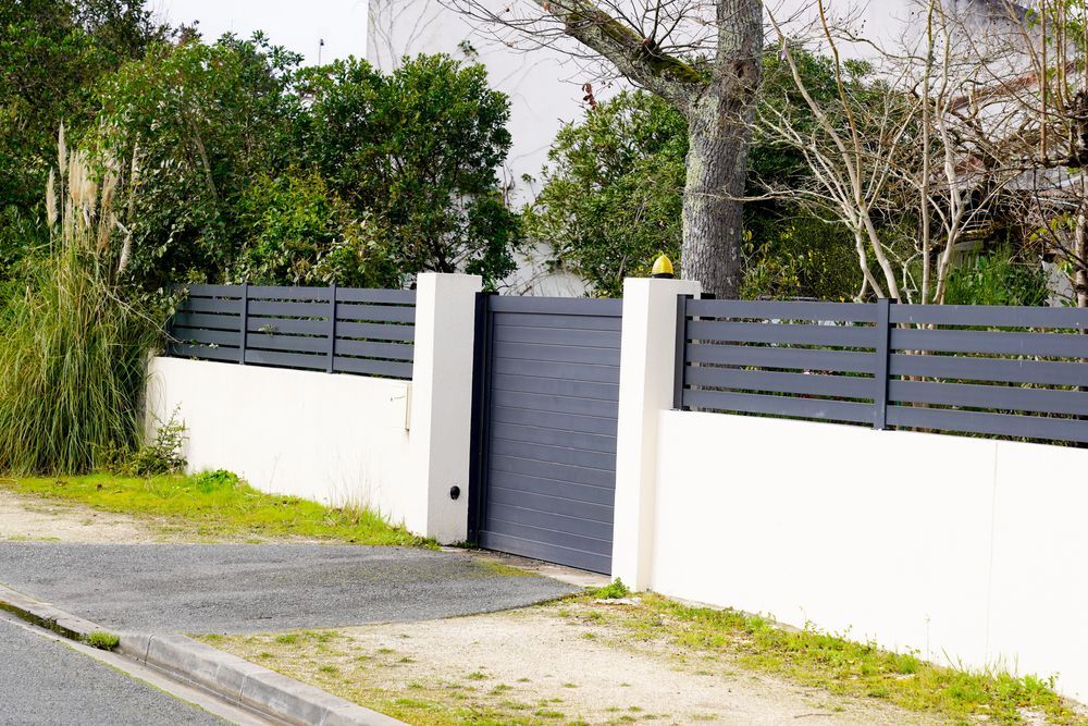Gray Gate and Fence Atop a White Wall, in Front of A House and Greenery — Sunshine Gates in Mountain Creek, QLD