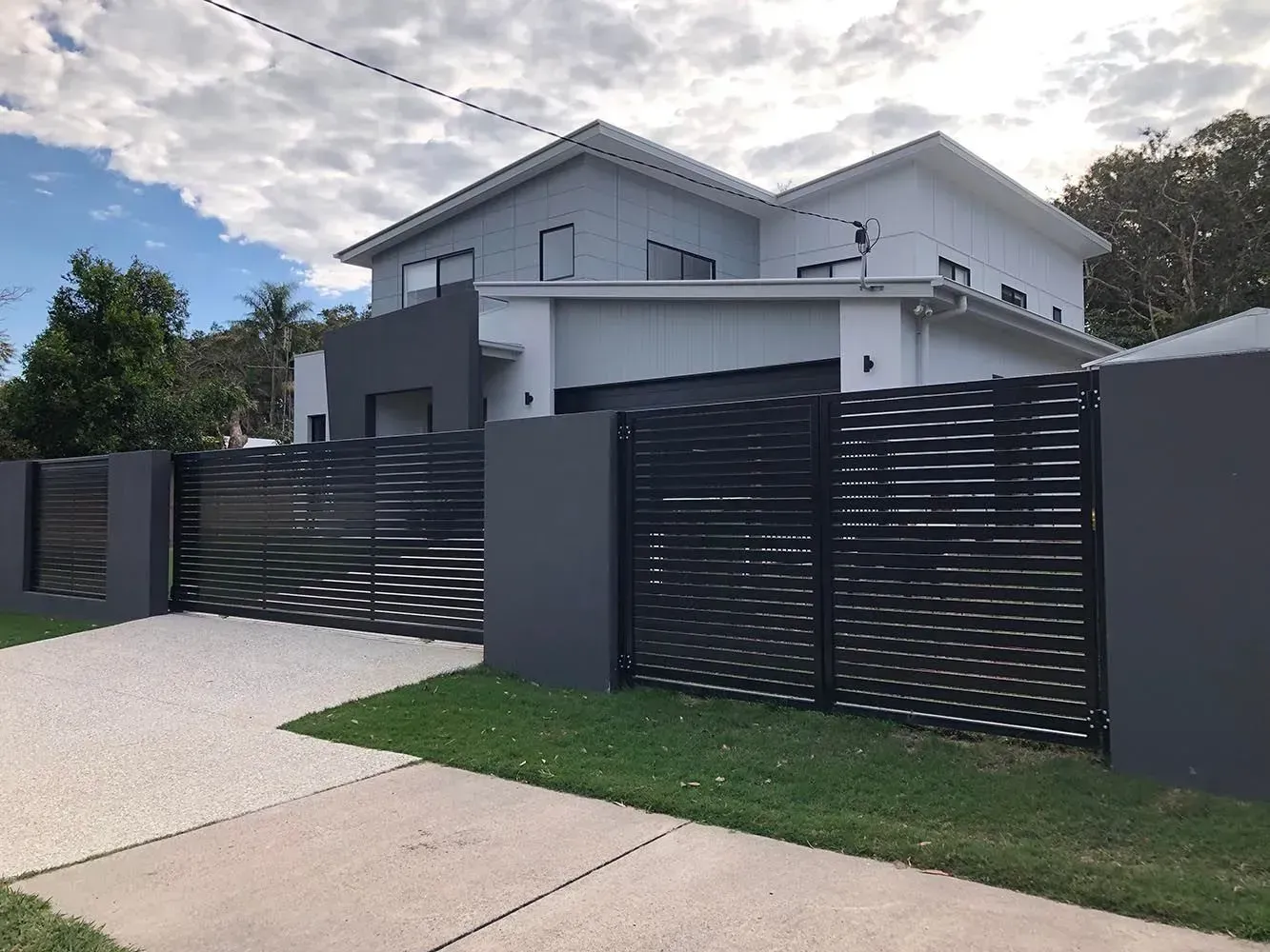 A large white house with a black fence in front of it. — Sunshine Gates in Kunda Park, QLD