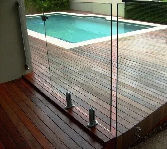 A swimming pool is behind a glass fence on a wooden deck. — Sunshine Gates in Kunda Park, QLD
