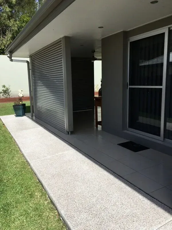 Concrete walkway along a gray house with a sliding glass door and a slatted screen — Sunshine Gates in Buderim, QLD