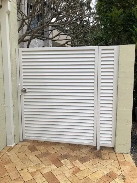 A white gate is sitting on top of a brick driveway. — Sunshine Gates in Kunda Park, QLD