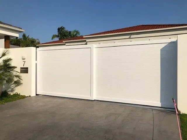 A white sliding gate is sitting in front of a house. — Sunshine Gates in Kunda Park, QLD