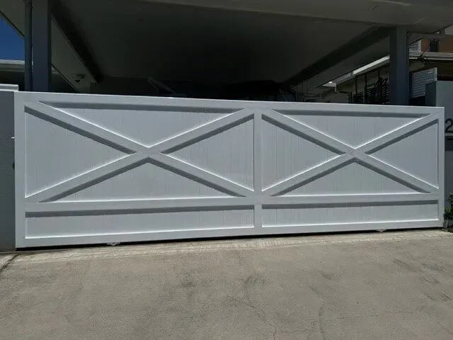 A white gate with crosses on it is sitting in front of a building. — Sunshine Gates in Kunda Park, QLD