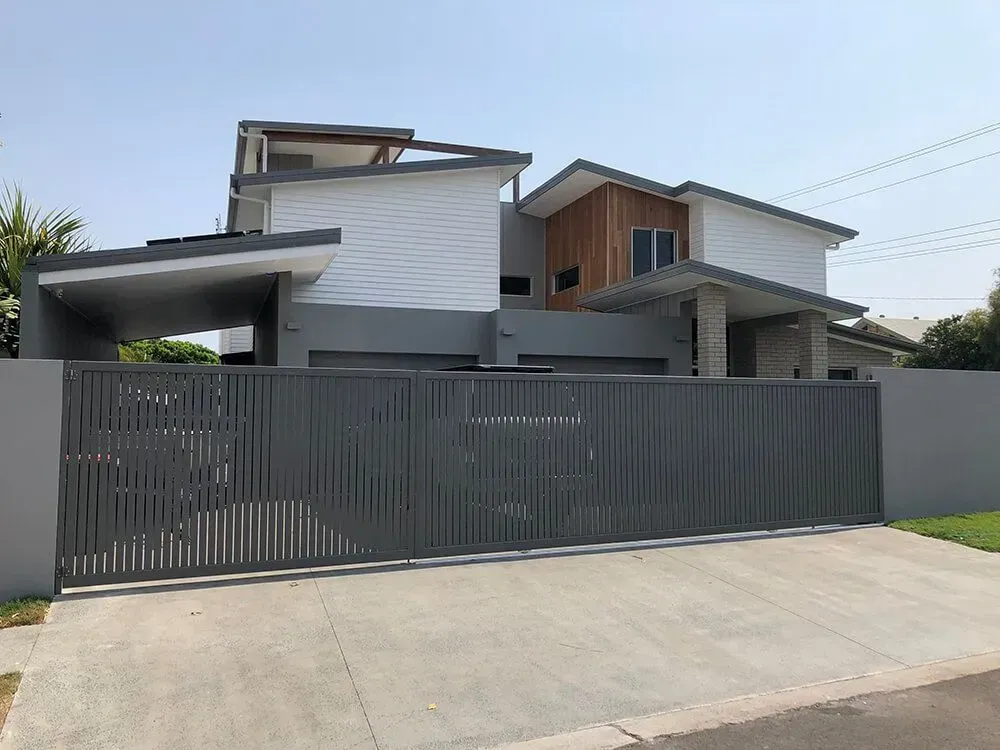 A Black and White Fence With a House in the Background — Sunshine Gates in Mooloolaba, QLD