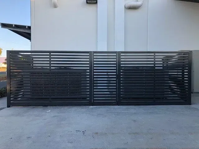 A black fence is sitting in front of a white building. — Sunshine Gates in Kunda Park, QLD