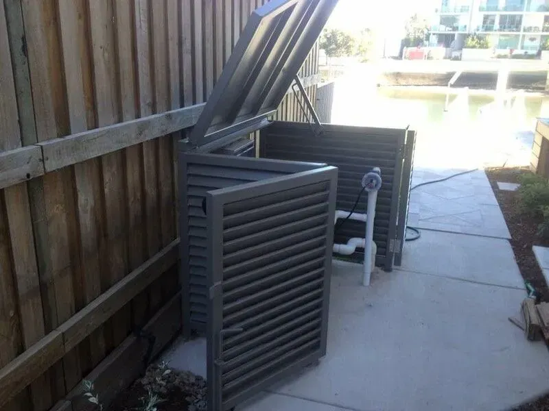 A metal box with the lid open is sitting on a sidewalk next to a wooden fence. — Sunshine Gates in Kunda Park, QLD