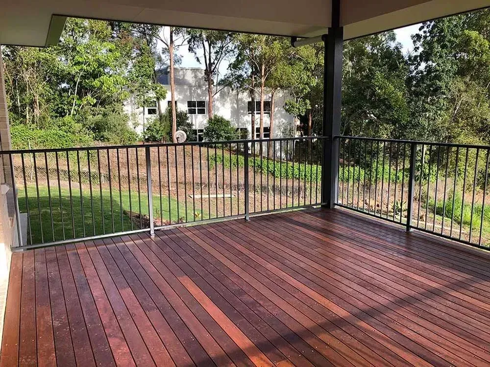 An empty wooden deck with a metal railing and a view of a house. — Sunshine Gates in Kunda Park, QLD