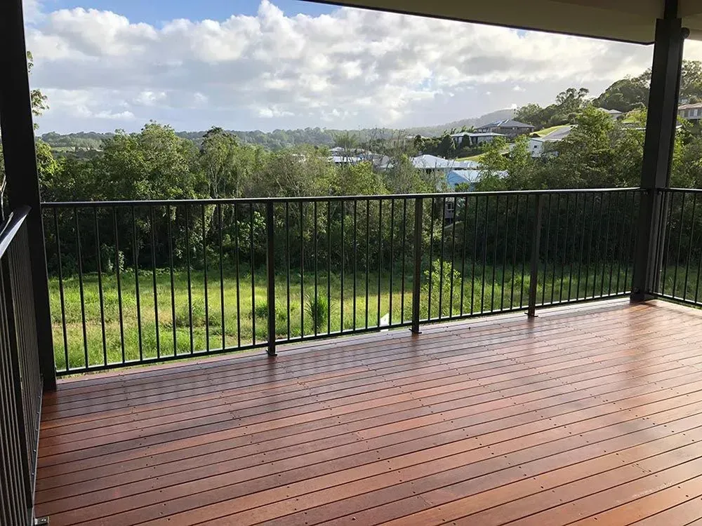 A wooden deck with a metal railing and a view of a field — Sunshine Gates in Kunda Park, QLD