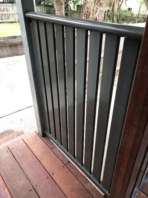 A close up of a black railing on a wooden deck. — Sunshine Gates in Kunda Park, QLD