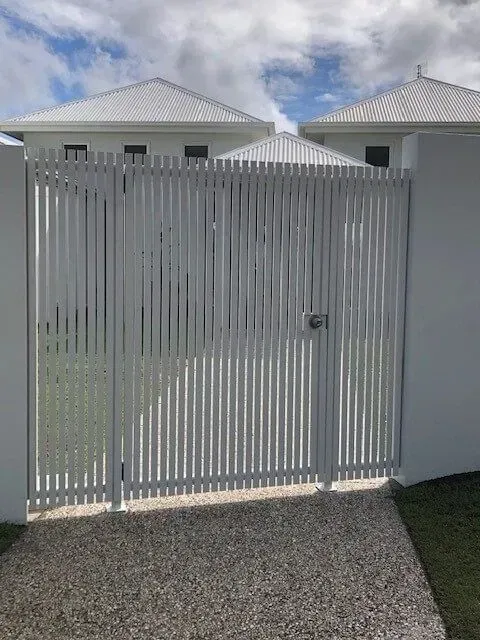 A white gate is sitting in front of a white house. — Sunshine Gates in Kunda Park, QLD