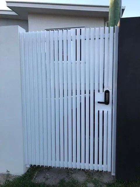A white gate with a black handle is sitting in front of a house. — Sunshine Gates in Kunda Park, QLD