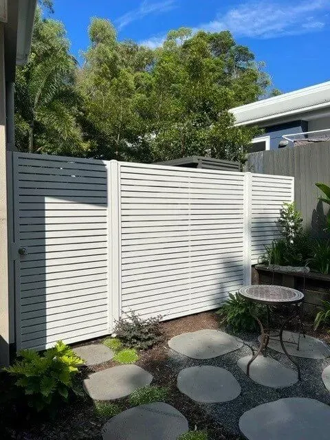 A white fence surrounds a garden with a table in the middle of it. — Sunshine Gates in Kunda Park, QLD