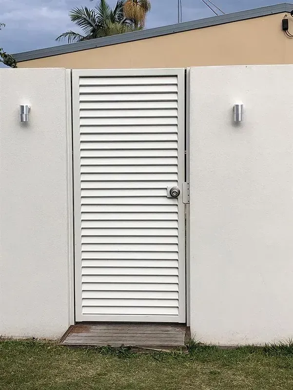 A white door with shutters on it is sitting in front of a white wall. — Sunshine Gates in Kunda Park, QLD
