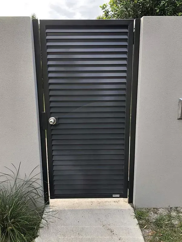 A black gate is sitting next to a white wall. — Sunshine Gates in Kunda Park, QLD