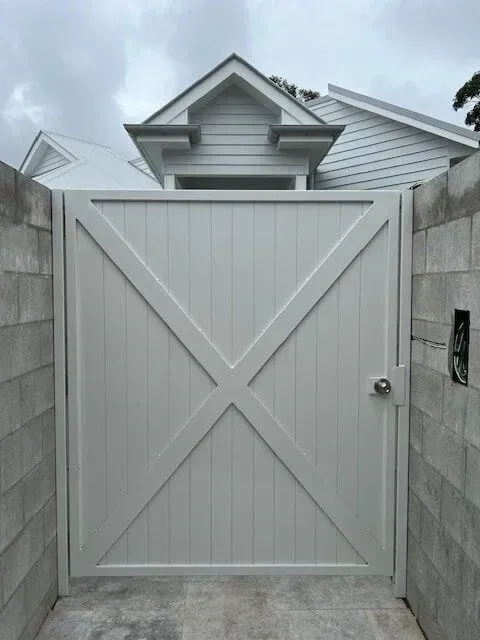 A white gate is between two brick walls in front of a house. — Sunshine Gates in Kunda Park, QLD