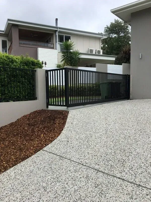 A driveway with a fence and a house in the background. — Sunshine Gates in Kunda Park, QLD