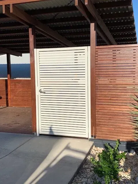 A white gate with a wooden fence behind it. — Sunshine Gates in Kunda Park, QLD