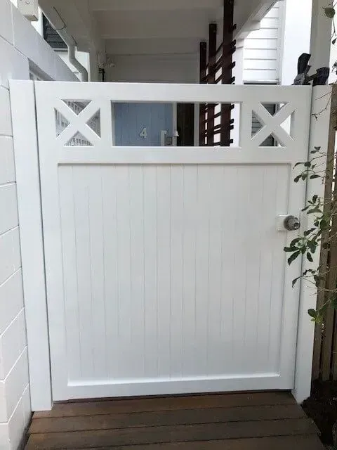 A white gate is sitting on a wooden deck next to a building. — Sunshine Gates in Kunda Park, QLD