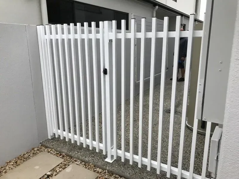 A white fence with a gate is sitting next to a building. — Sunshine Gates in Kunda Park, QLD