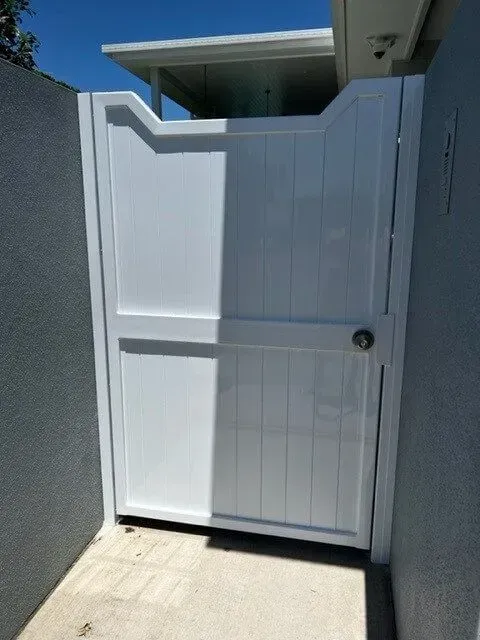 A white gate is sitting on the side of a building. — Sunshine Gates in Kunda Park, QLD