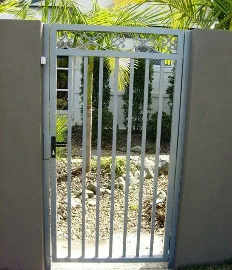 A metal gate leading to a garden with palm trees in the background. — Sunshine Gates in Kunda Park, QLD